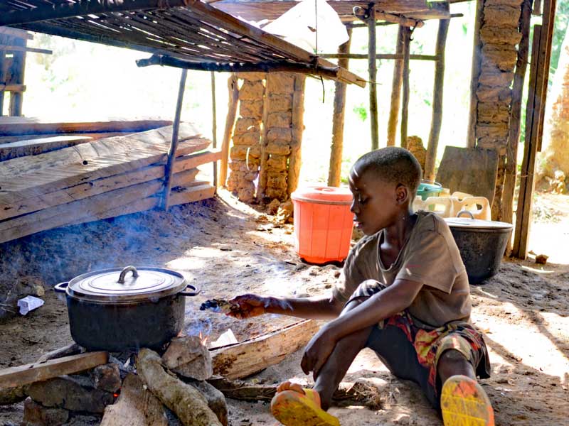 Un enfant Pygmée Bagyeli fait griller eu  épi de maïs