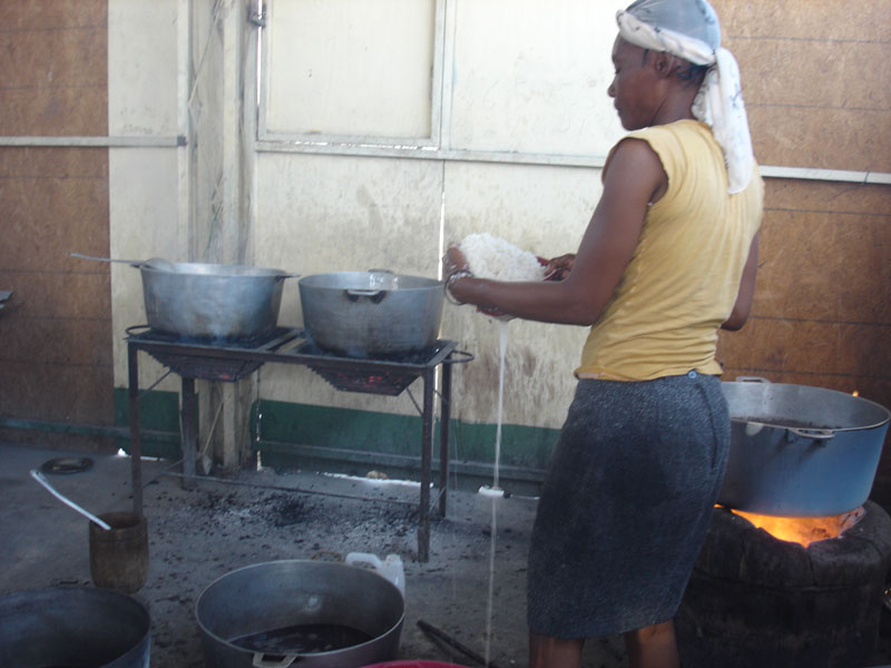 Une des cuisinières de l'école St Alphonse de Cité Soleil en Haïti prépare le repas de la cantine scolaire