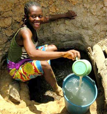 Jeune fille puisant de l'eau dans une source souillée en RD Congo