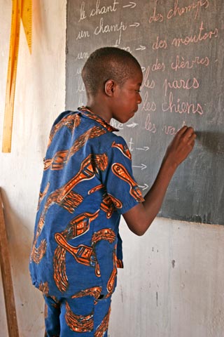 Elève de l'école de la deuxième chance à Guiè au Burkina Faso écrivant au tableau noir