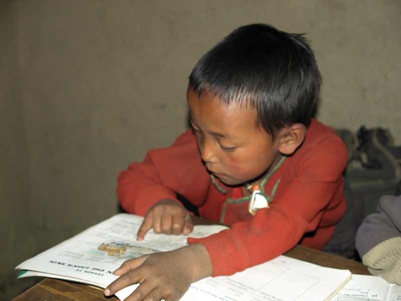 Enfant tibétain du Haut Dolpo apprenant à lire à l'école de Ting Kyu au Nepal