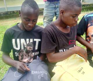 Les jeunes Bagyeli brodent leur nom sur leur uniforme scolaire