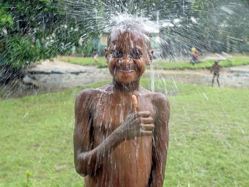 Enfant Pygmée de Bipindi au Cameroun jouant sous la pluie