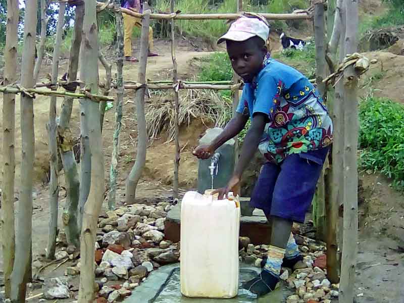 Enfant puisant de l'eau à l'une des bornes fontaines de Kitolu en RDC