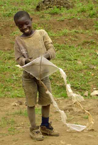 Jeune garçon rwandais confectionnant un cerf-volant