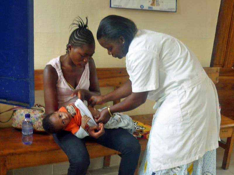 Infirmière du dispensaire de Ndako Ya Biso soignant le bébé d'une fille de la rue
